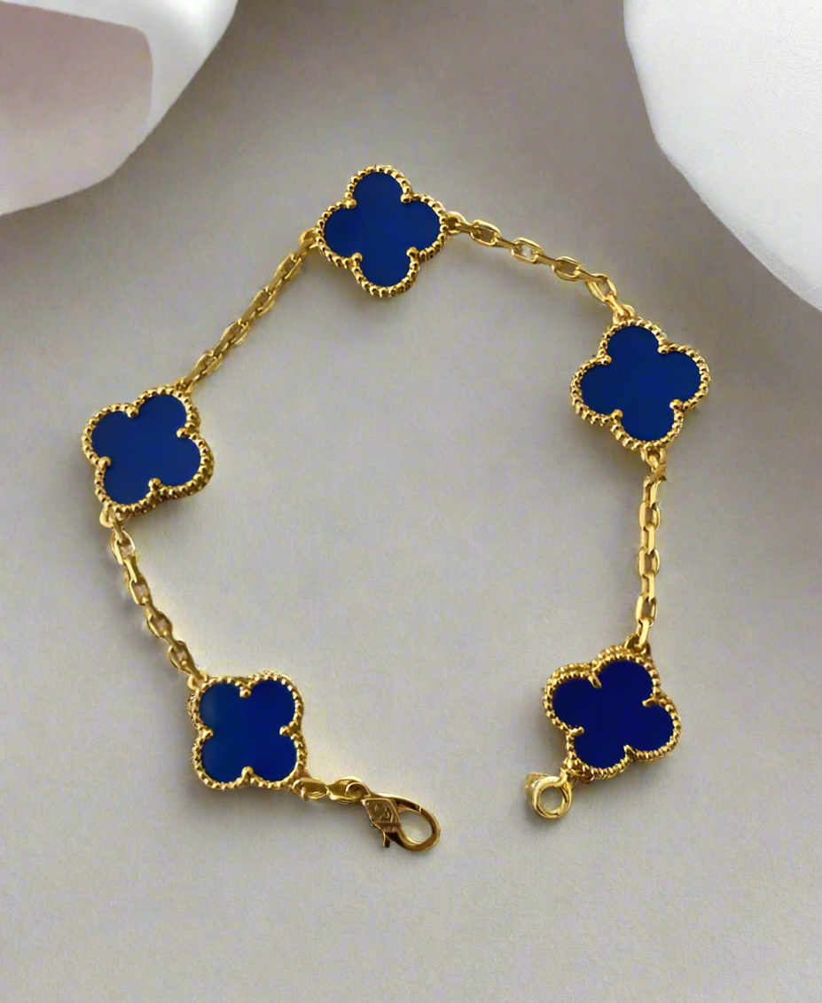 Gold bracelet with blue clover-shaped charms on a light gray background
