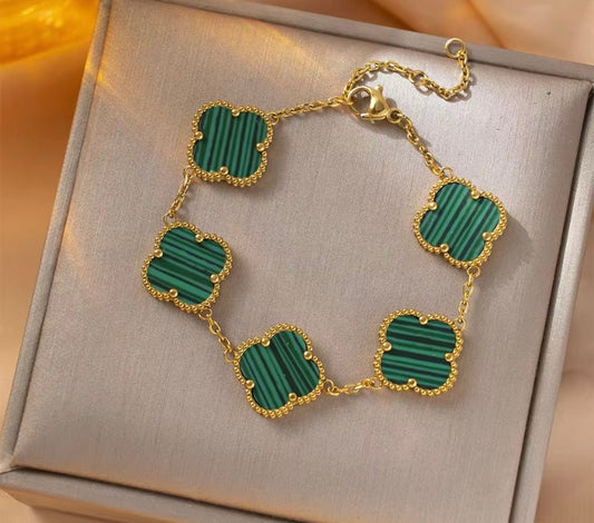 Gold bracelet with green clover on a beige box